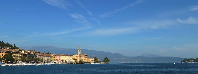 Trip Alps beliebte Urlaubsziele am Gardasee -  Mit einer Fläche von 370 km² ist der Gardasee der größte See Italiens. Es liegt am Fuße der Alpen und erstreckt sich über drei Staaten: Lombardei, Venetien und Trentino. Die maximale Tiefe des Sees beträgt 346 m, er hat eine längliche Form und sein nördliches Ende ist sehr schmal. Dort ist der See von den Bergen der Gruppo di Baldo umgeben. Du trittst aus deinem gemütlichen Hotelzimmer und es begrüßt dich die warme italienische Sonne. Du blickst auf den atemberaubenden Gardasee, der in zahlreichen Blautönen schimmert - von tiefem Dunkelblau bis zu funkelndem Türkis. Majestätische Berge umgeben dich, während die Brise sanft deine Haut streichelt und der Duft von blühenden Zitronenbäumen deine Nase kitzelt. Du schlenderst die malerischen, engen Gassen entlang, vorbei an farbenfrohen, blumengeschmückten Häusern. Vereinzelt unterbricht das fröhliche Lachen der Einheimischen die friedvolle Stille. Du fühlst dich wie in einem Traum, der nicht enden will. Jeder Schritt führt dich zu neuen Entdeckungen und Abenteuern. Du probierst die köstliche italienische Küche mit ihren frischen Zutaten und verführerischen Aromen. Die Sonne geht langsam unter und taucht den Himmel in ein leuchtendes Orange-rot - ein spektakulärer Anblick.